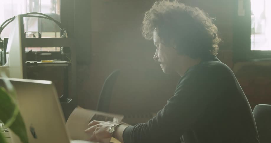 A man is sitting at a office desk intensely working on a project