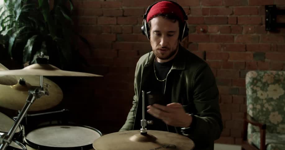 Drummer wearing headphones prepares to play drums