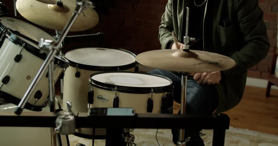 A man plays the drums wearing headphones and swaying to the music