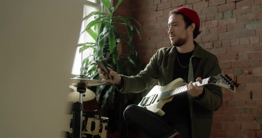 Man plays a bass guitar next to the drum set