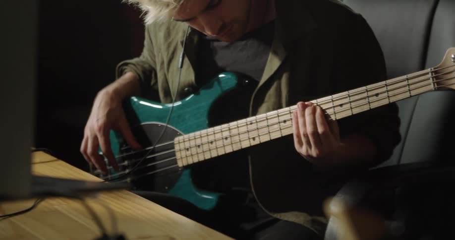 A man with headphones sitting in a chair playing an electric guitar