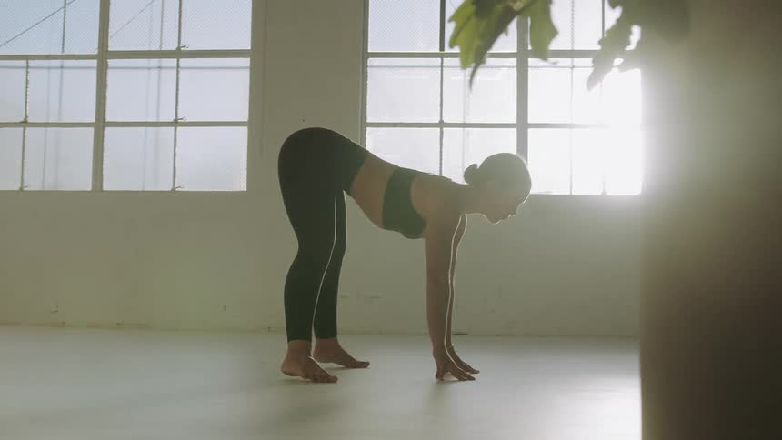 A woman does a hand stand and then lowers her body while doing yoga