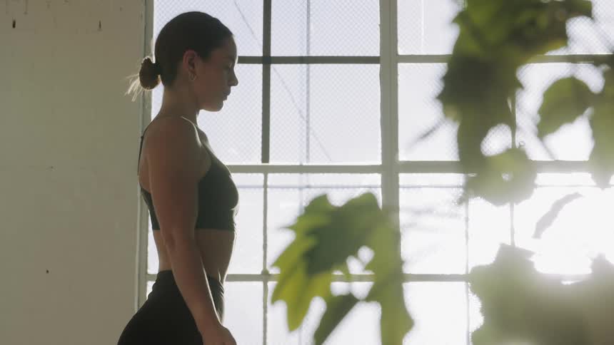 A woman takes a deep breath while standing and meditating