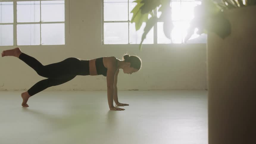 Woman stretching and practicing yoga moves at an empty room