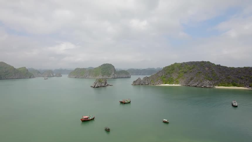 Boats are anchored off shore of islands as people walk on the sandy beaches