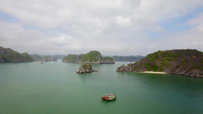 Boats in the green tropical waters off a group of small rocky islands