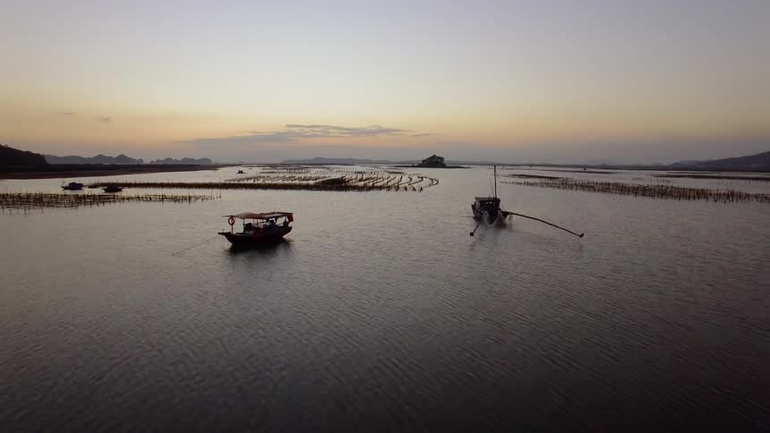 Fishing boats anchored near aquaculture nets and pylons