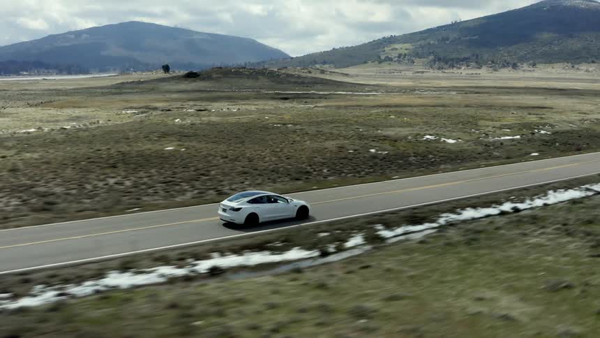 Aerial view of a car driving along highway through plains