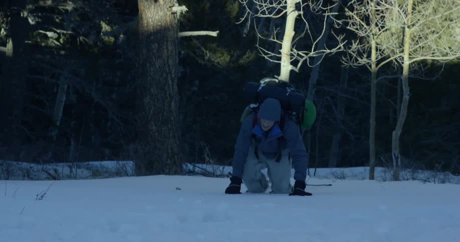 White man hiking at forest and walking through the snow and falling down