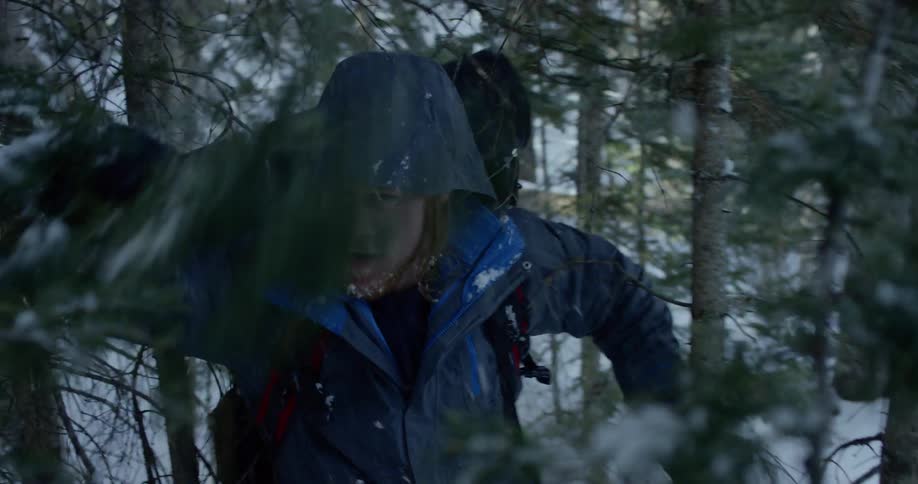 Man goes uphill through snow in the woods
