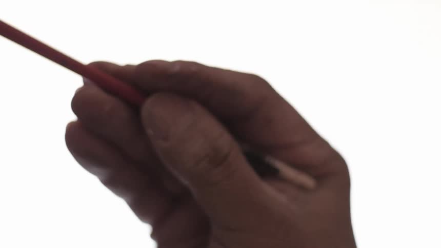 A hand holding a thin wooden paint brush making brushing strokes