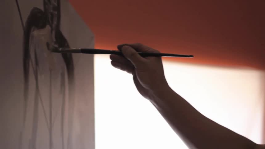 Man painting on a canvas near a window