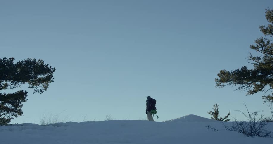 A man hikes up a snow covered slope