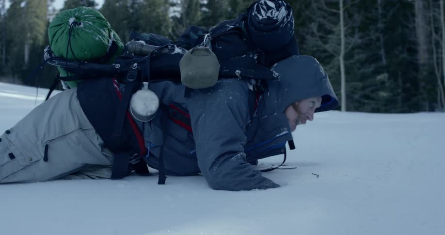 Injured man falling in the snow while backpacking in the mountains