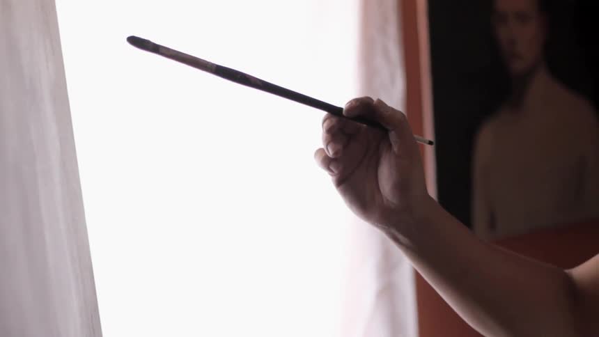 A person holding a pencil about to paint a painting frame