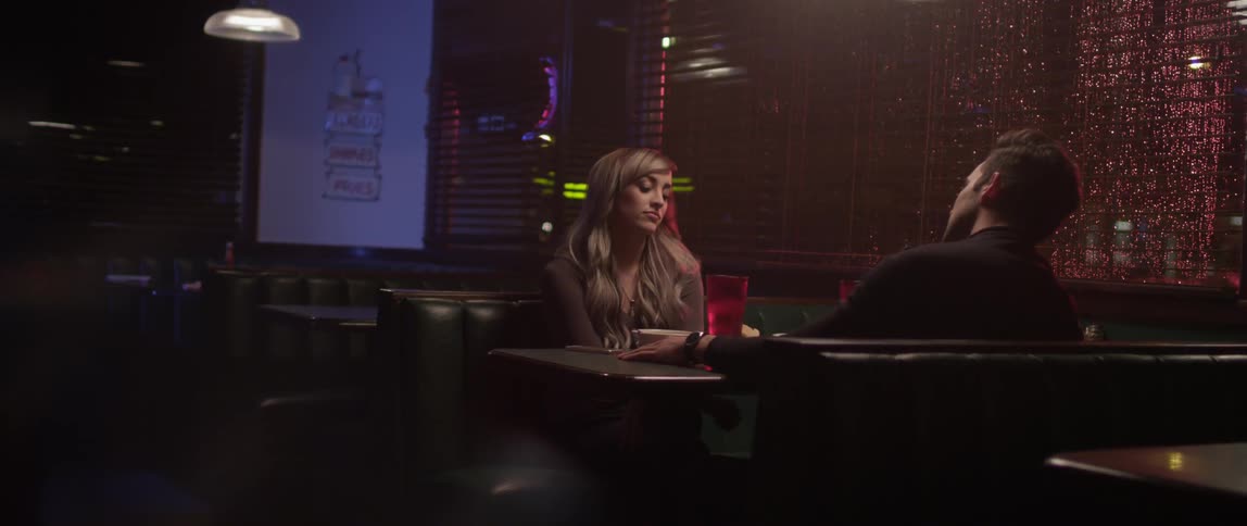 A man and woman talk sitting in a restaurant booth