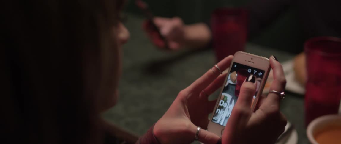 A woman uses a cell phone to photograph food and post it online