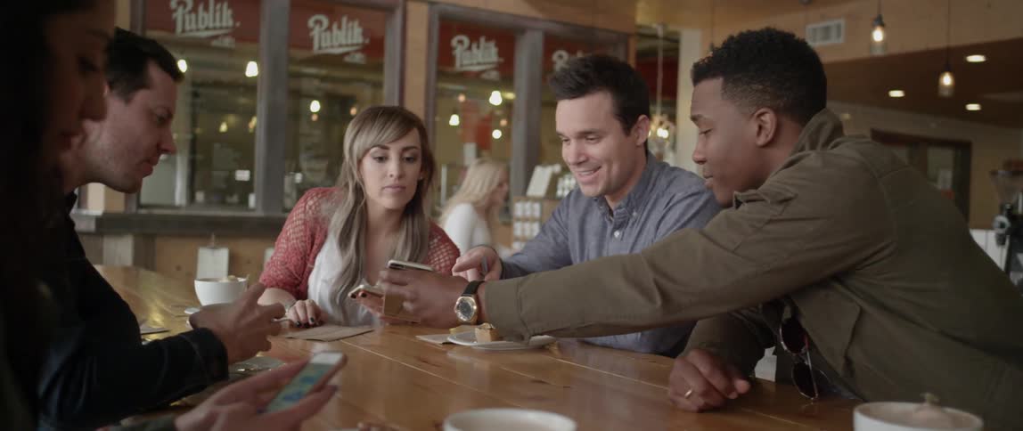 People at a cafe table look at their cell phones