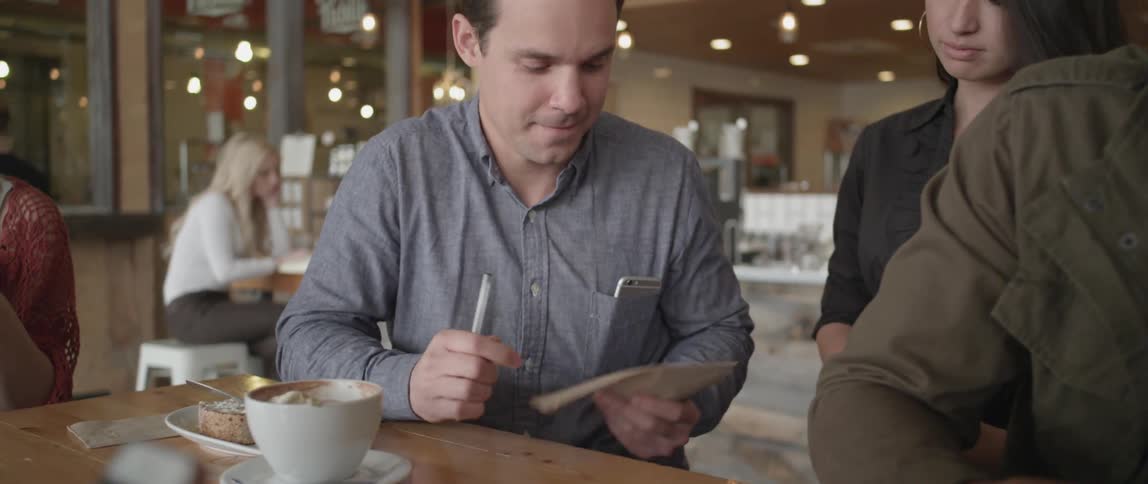 A man writes on a piece of paper and hands it to a woman