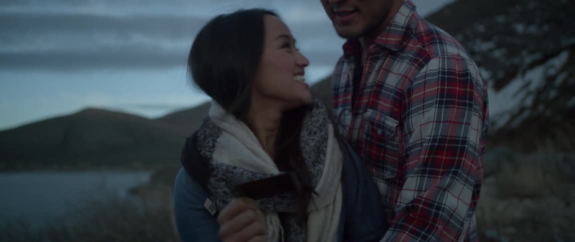 A man and woman romantically hug and look at a picture on a cool overcast evening