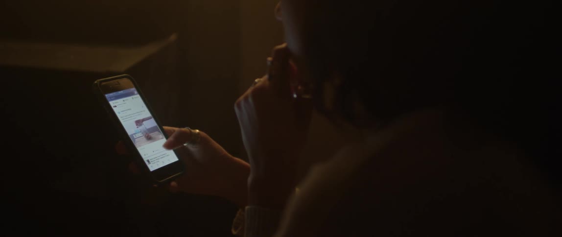 Woman scrolls on a smartphone in the dark
