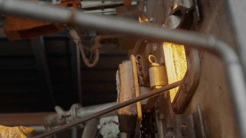 Person prods furnace with metal rod through small open door