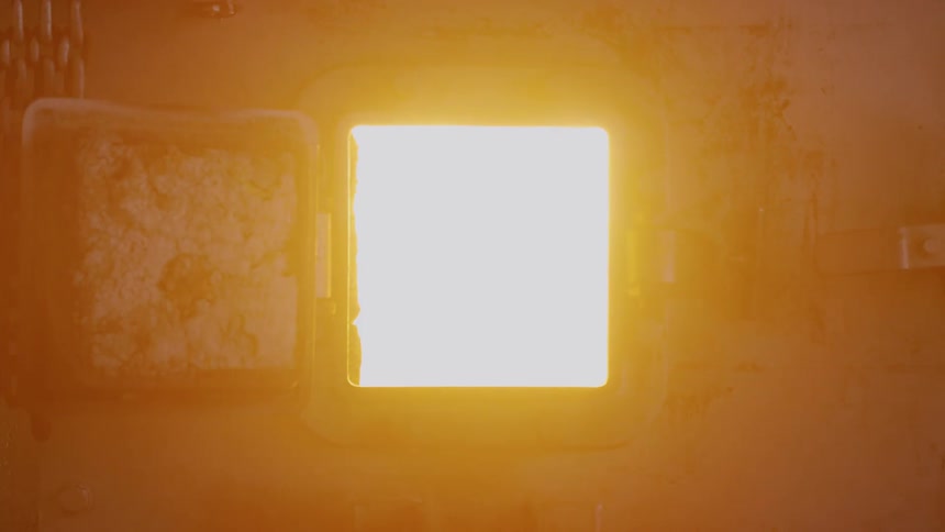 A person opens a small door to reveal fire