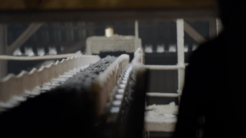 A man walks along a conveyor belt in a factory