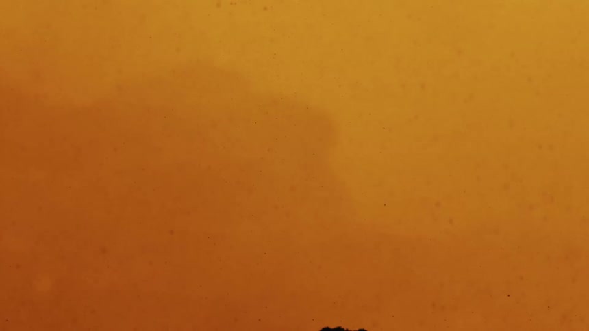 Debris and small particles float through a flaming background
