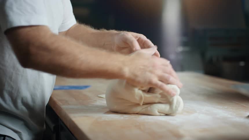 Man kneads the dough on the kitchen counter