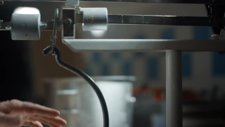 Person placing small dough piece on a scale in a restaurant kitchen