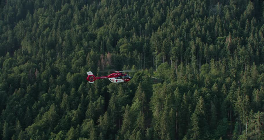 A helicopter flying over a large wooded area