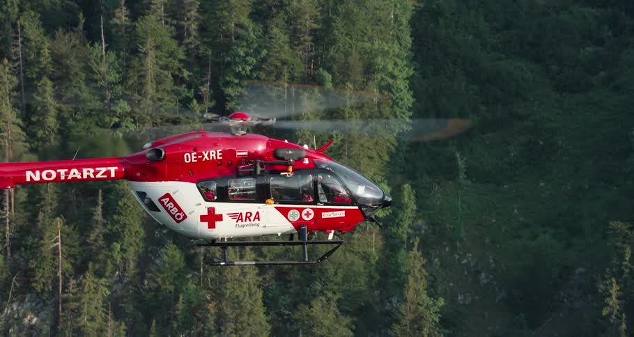 Slow motion shot of rescue helicopter flying through the mountains