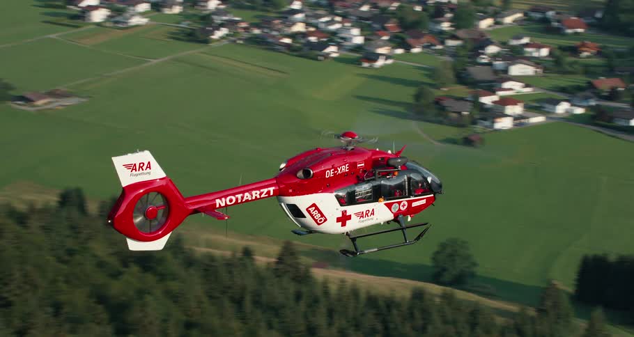 A helicopter flies over a small neighborhood toward a large building