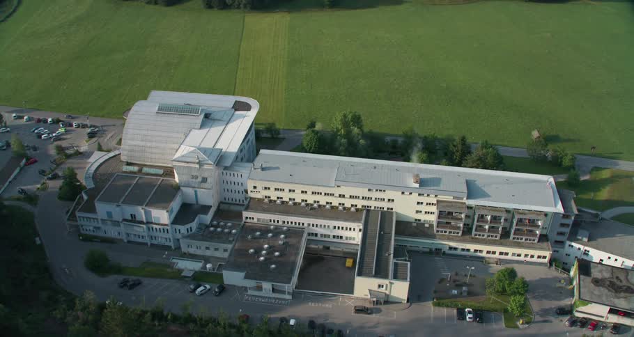 Vehicles are parked outside a large office building with a well manicured lawn
