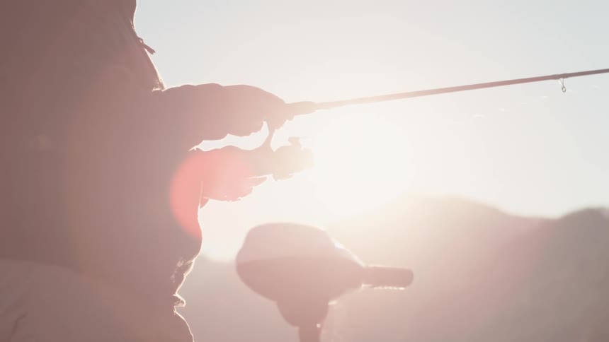 A man on a boat is fishing with a reel