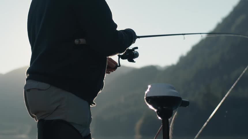 A person in a boat reeling in a fishing rod