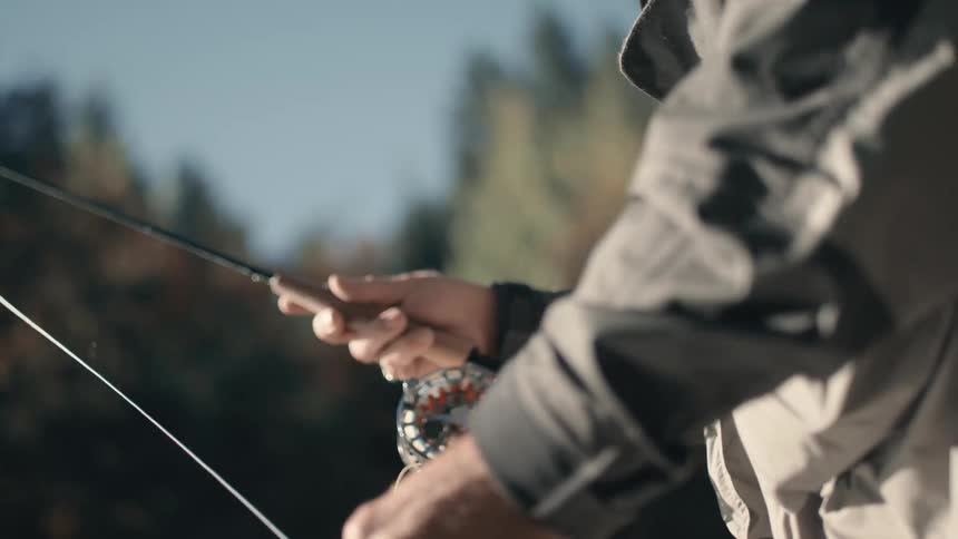 A fisherman throws out fishing line and reels it back