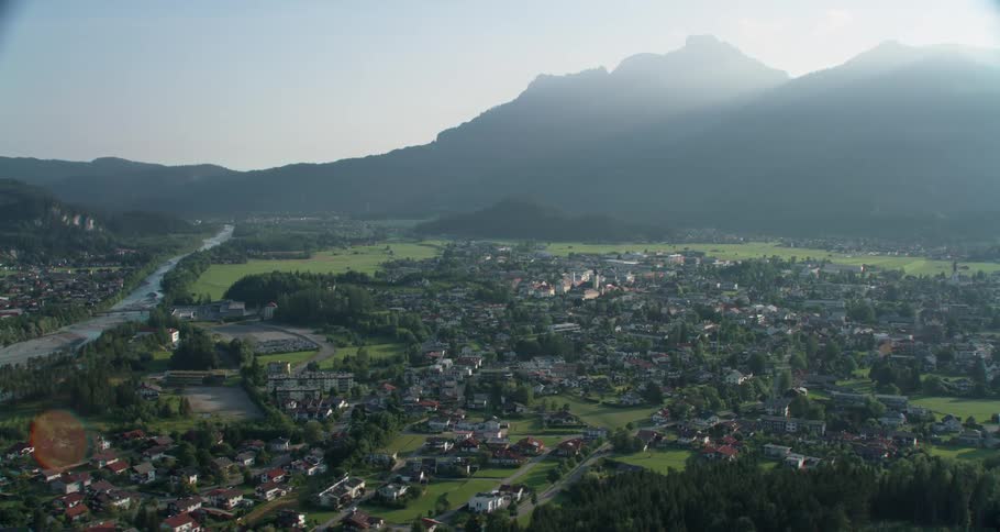 A rural town with mountains in the background as the sun rises over the mountains