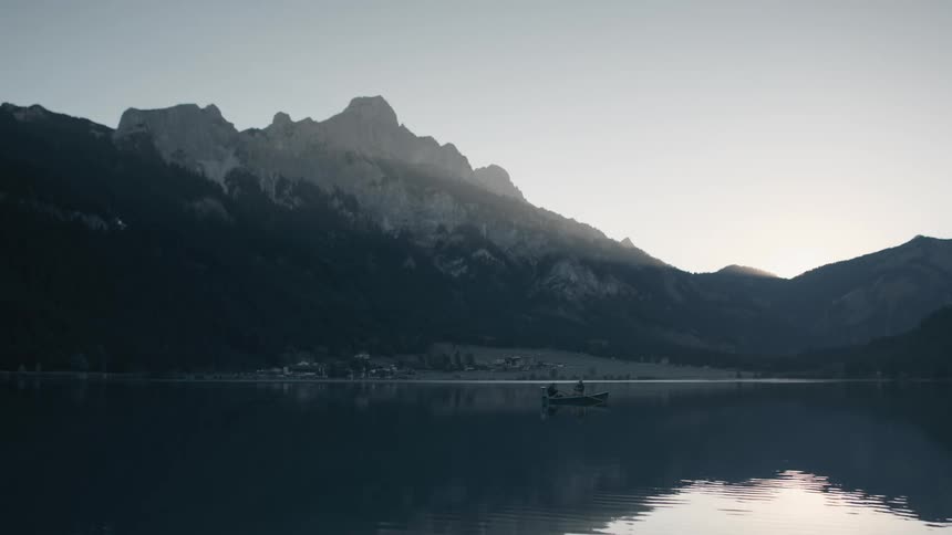 Fisherman on a boat fishing on lake at sunrise