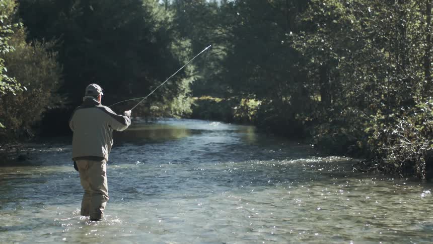 Fisherman fly fishing in a stream in the mountains