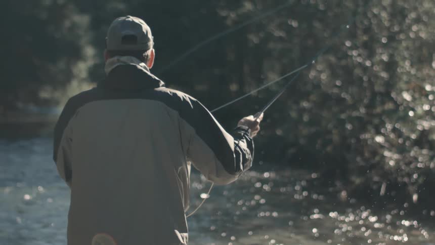 A man next to a river fly fishing