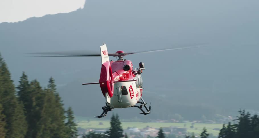 A helicopter flying over a forest with a town in the foreground