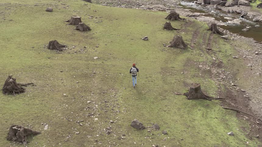 Aerial of a backpacker walking alone along a river bed