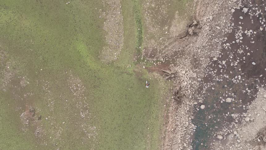 Person walks over the green land near the rocks