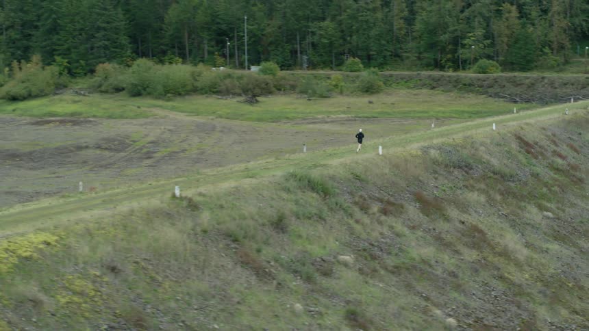 Person running alone through a dirt road in a forest area