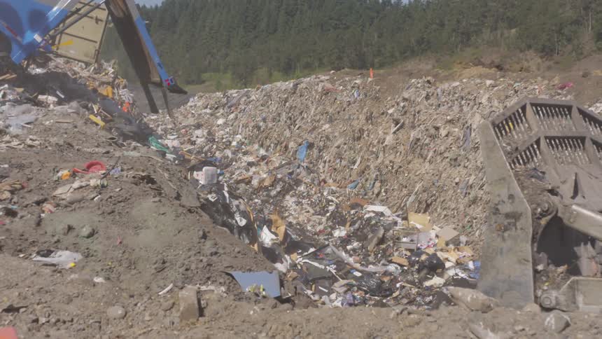 Bulldozer pushes the piles of rubbish in the garbage dump
