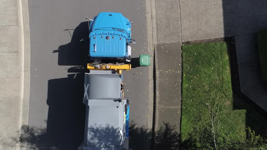 Point off view of trash truck picking up trash cans in the neighborhood