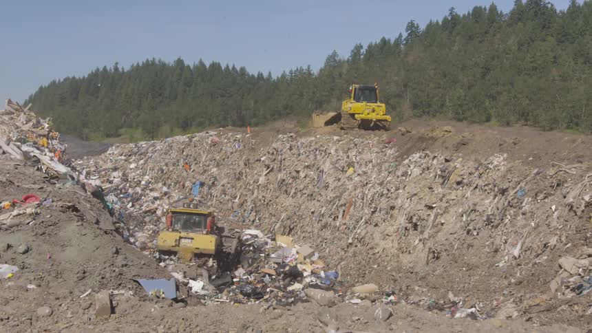 Bulldozers push piles of rubbish in the garbage dump