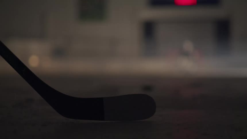 Hockey stick in position on the ice with puck in the distance